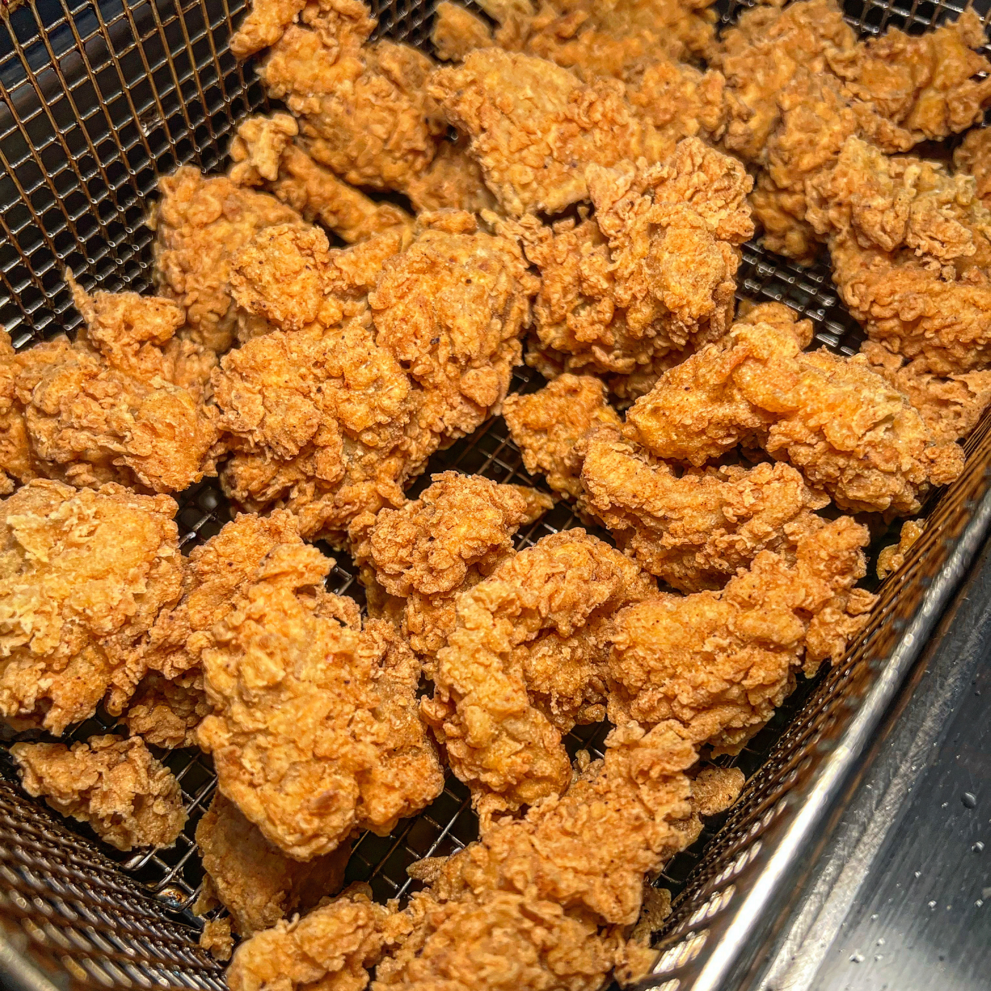 vegan chicken pieces breaded and deep fried like vegan KFC in a deep fryer metal basket, serving suggestion